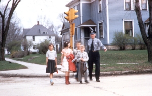 Ed Donnelly helps students from Oswego's old Red Brick School cross Madison Street in the spring of 1957 with the help of traffic signal lights purchased by the Oswego Lions Club. (Little White School Museum photo by Everett Hafenrichter)